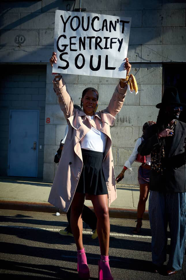 black woman hodling up "YOU CANT GENTRIFY SOUL" sign Trump DEI